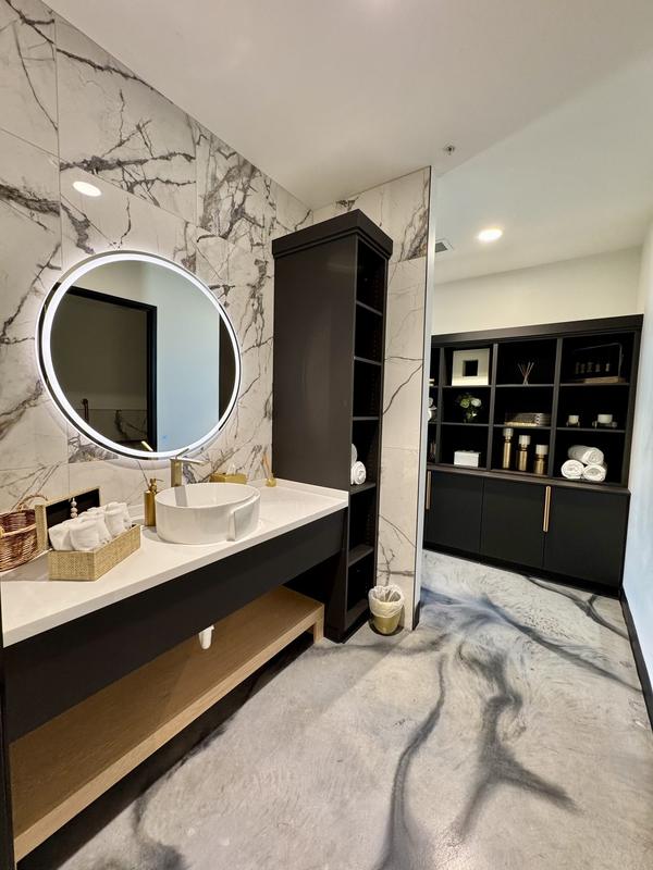 Restroom vanity with marble wall and spotless mirror