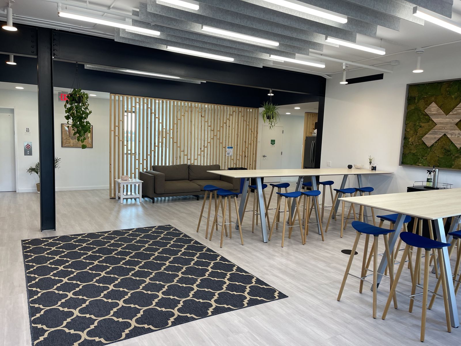 Open coworking commons with communal tables and a slatted timber screen