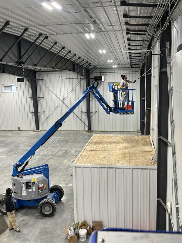 A team member on a boom lift cleaning a hangar wall