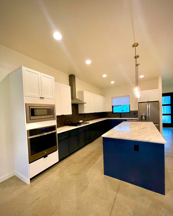 Newly finished kitchen with navy cabinetry, a marble island and polished concrete