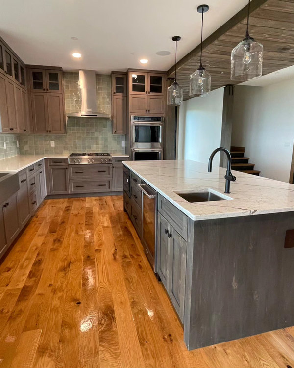Kitchen with grey-stained cabinetry, a marble island and white oak floors