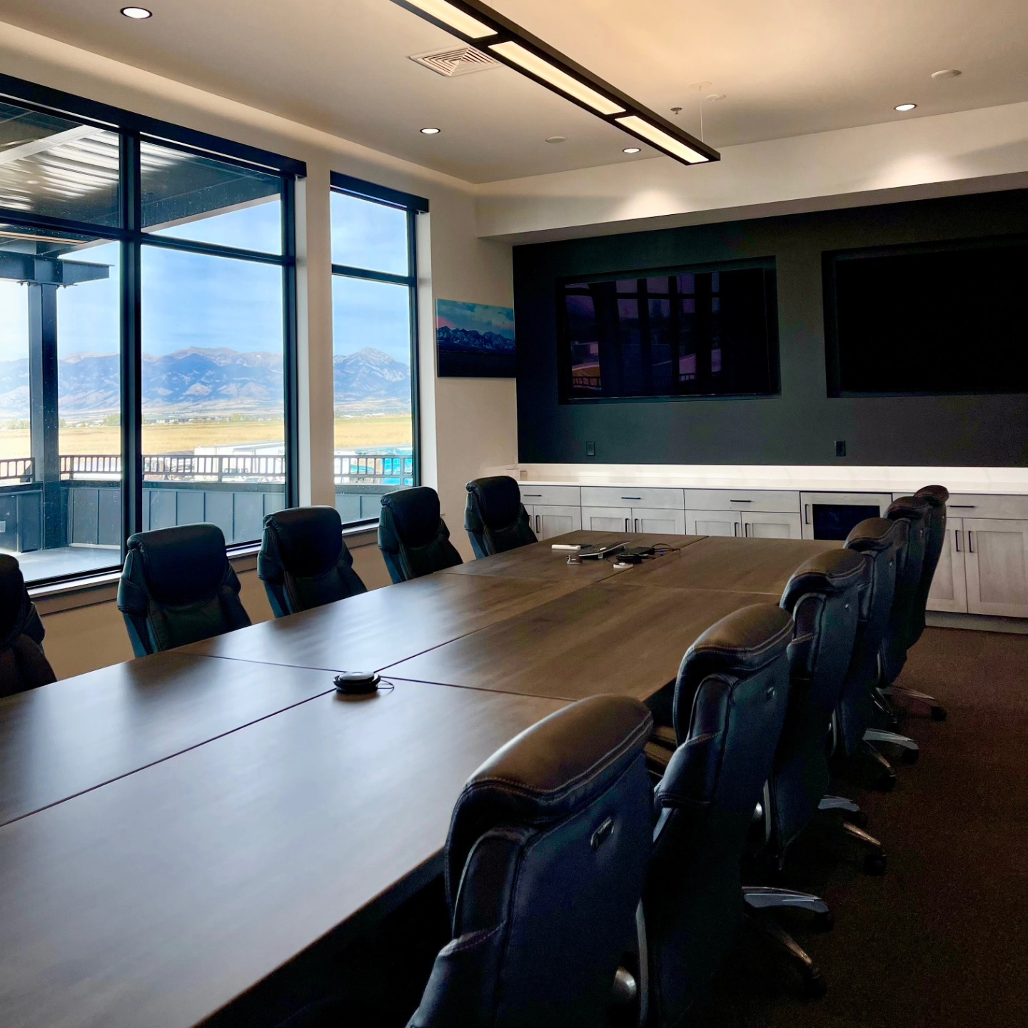 Boardroom with a long table and a mountain view through floor-to-ceiling glass