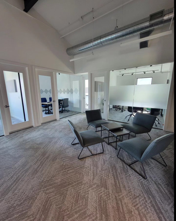 Office lounge with glass-walled meeting rooms and fresh carpet