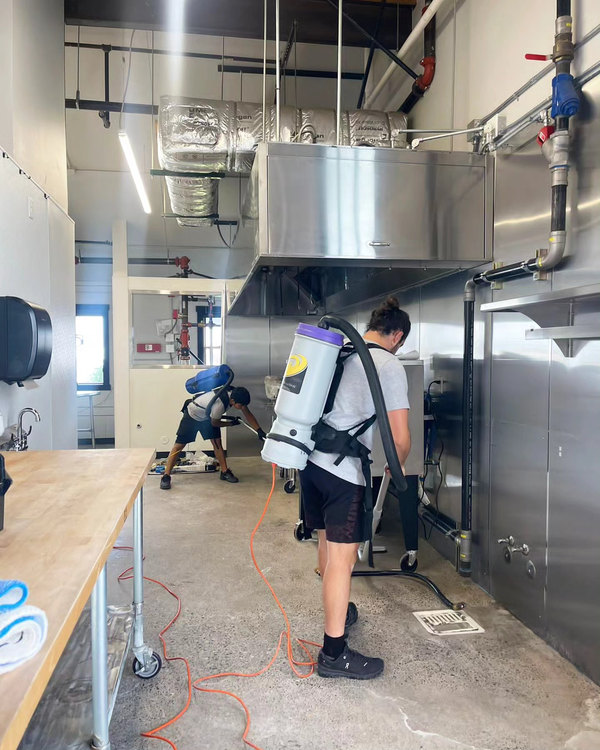 Two team members detailing a stainless commercial kitchen